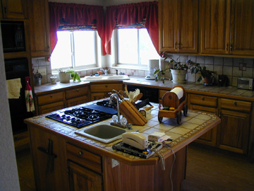 Custom kitchen with tile counter tops and a wood floor.......